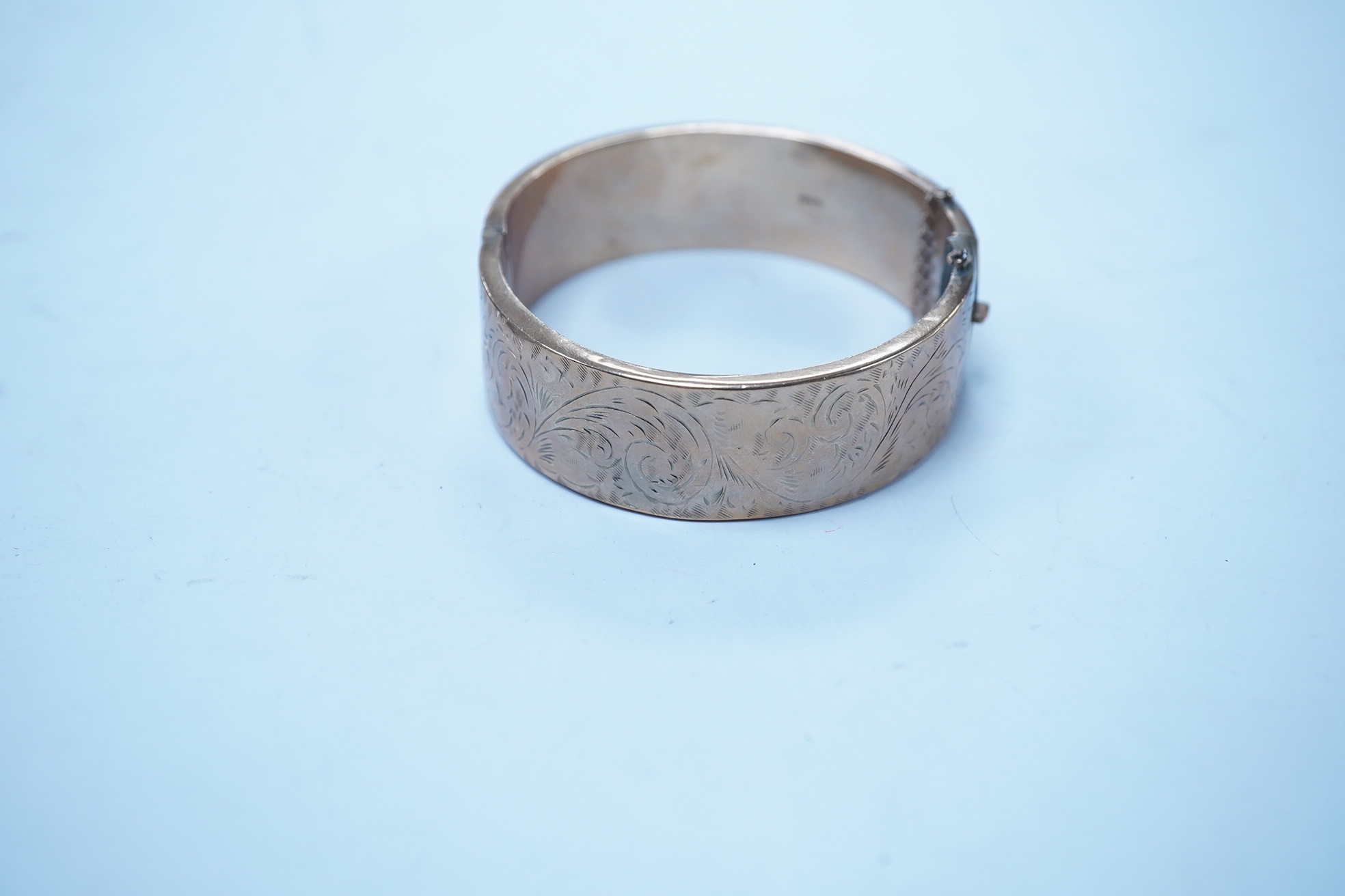 A 1960's engraved 9ct gold hinged bangle, 24.1 grams. Condition - poor